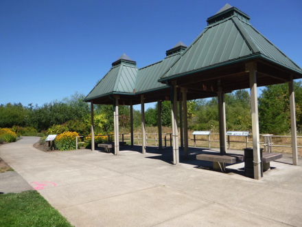 Covered wetland viewing area with benches, garbage cans and informational signage – next to butterfly garden